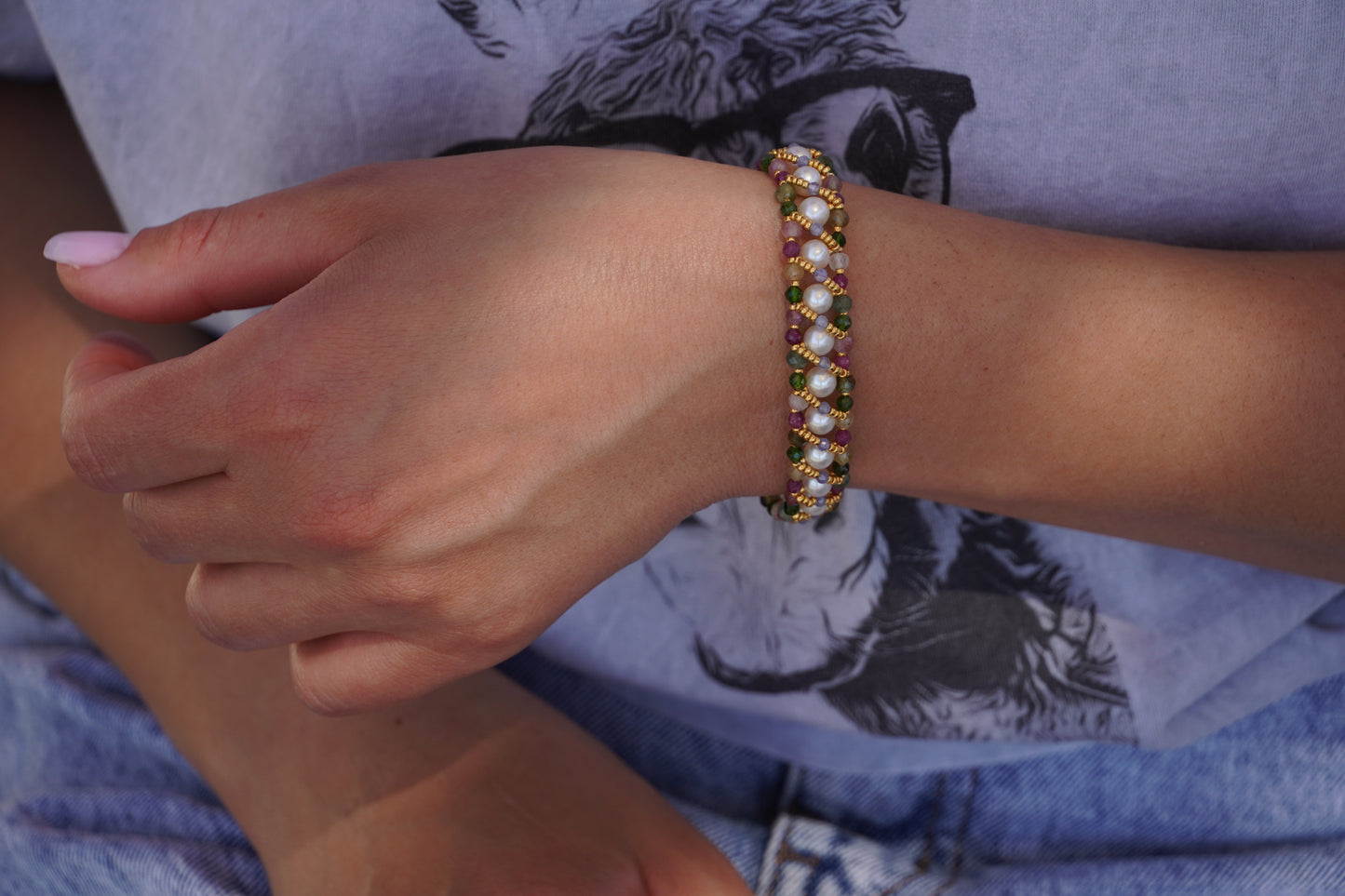 Close-up of a hand wearing a beaded bracelet with a blurred background