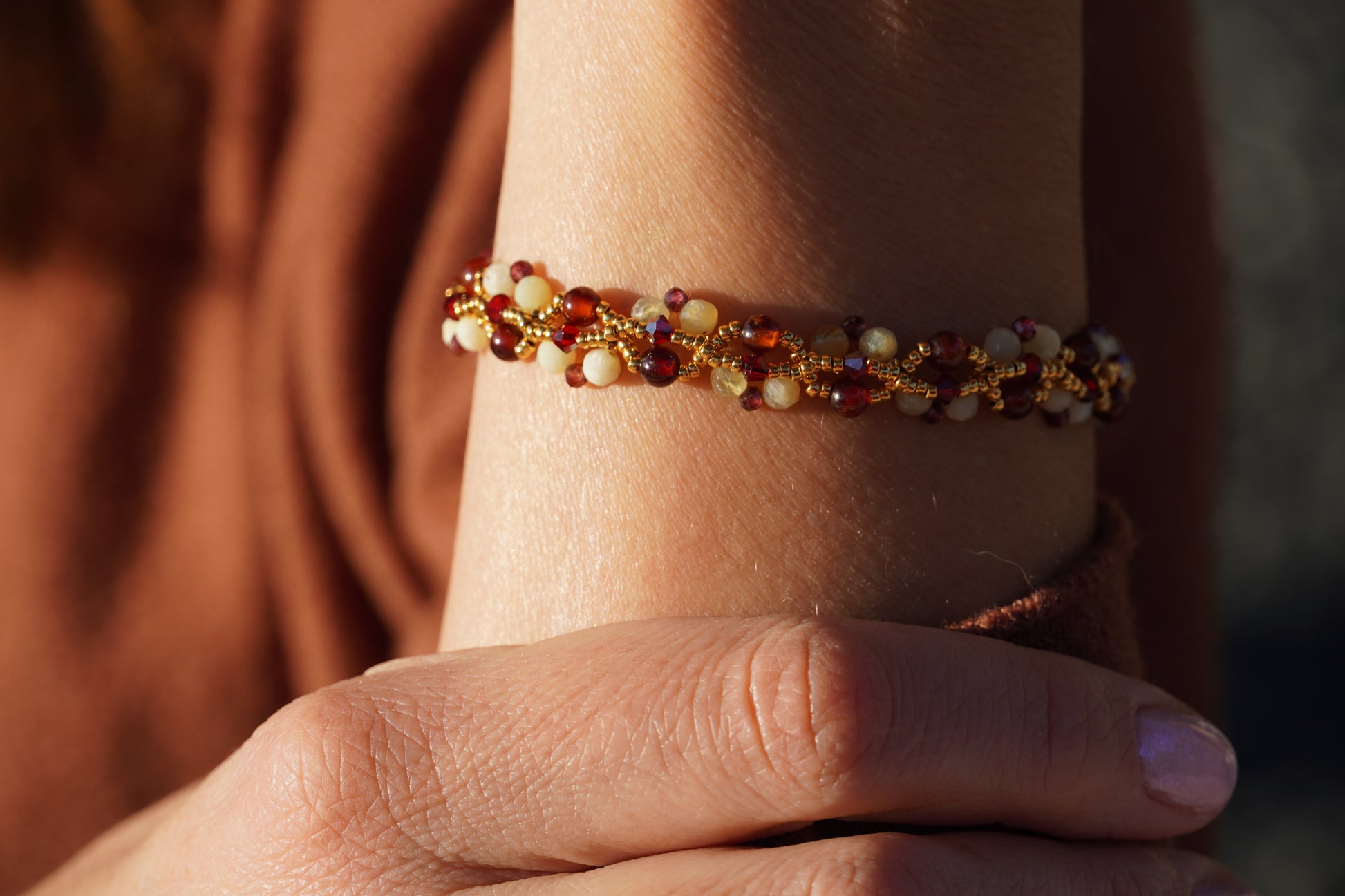 Close-up of a hand wearing a beaded bracelet with a blurred background