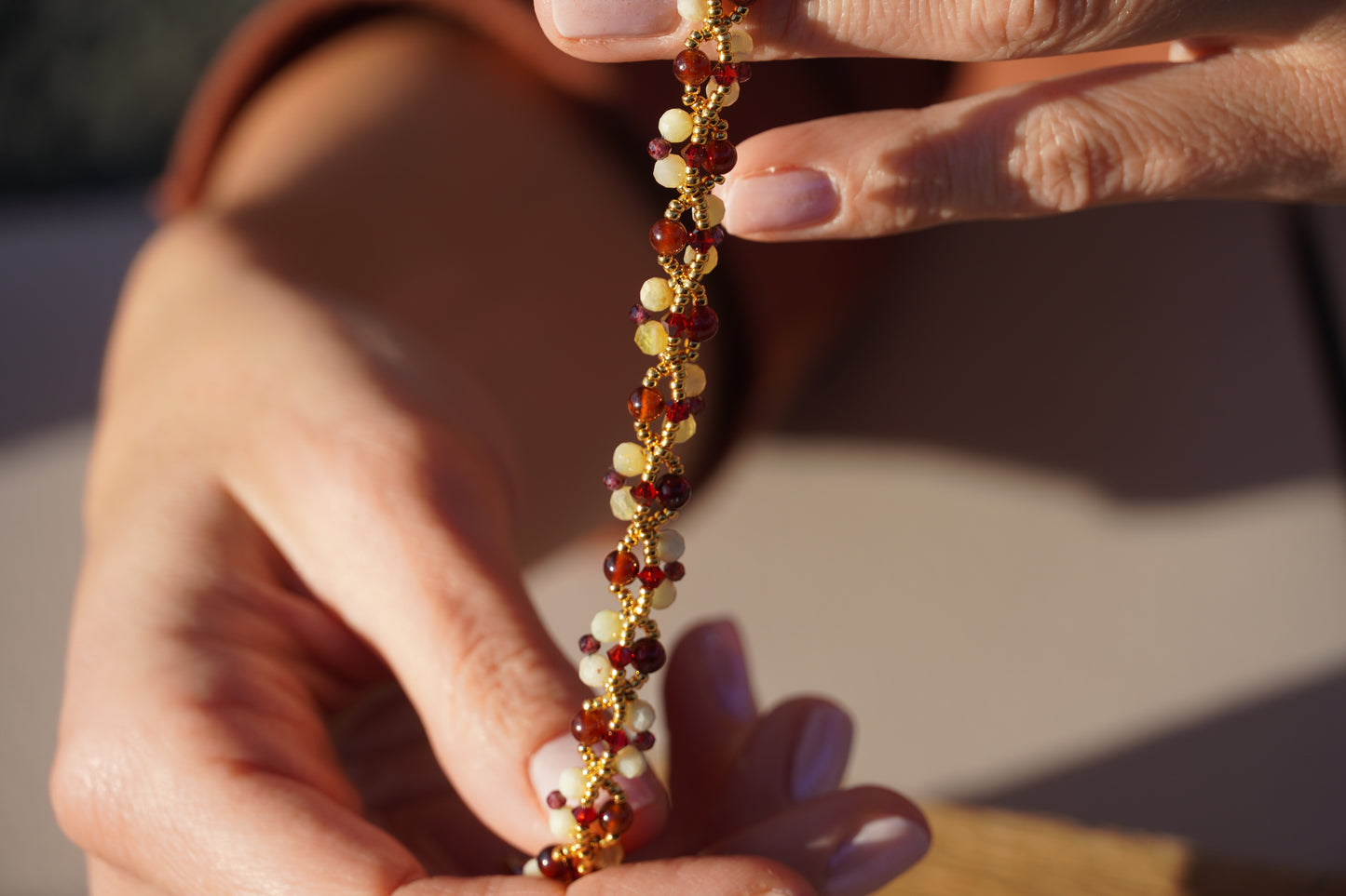Close-up of hands holding a beaded bracelet with a blurred background