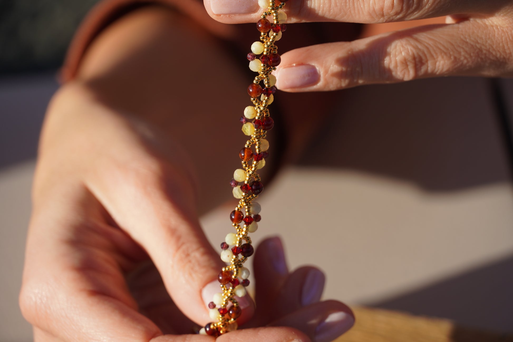 Close-up of hands holding a beaded bracelet with a blurred background