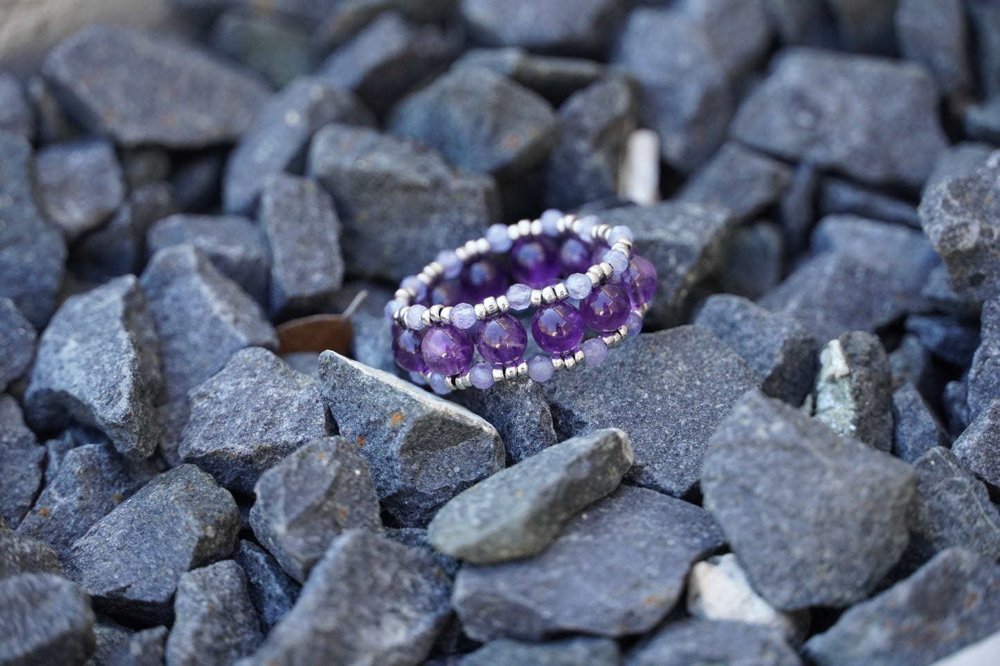 Amethyst and tanzanite ring on a bed of gray stones