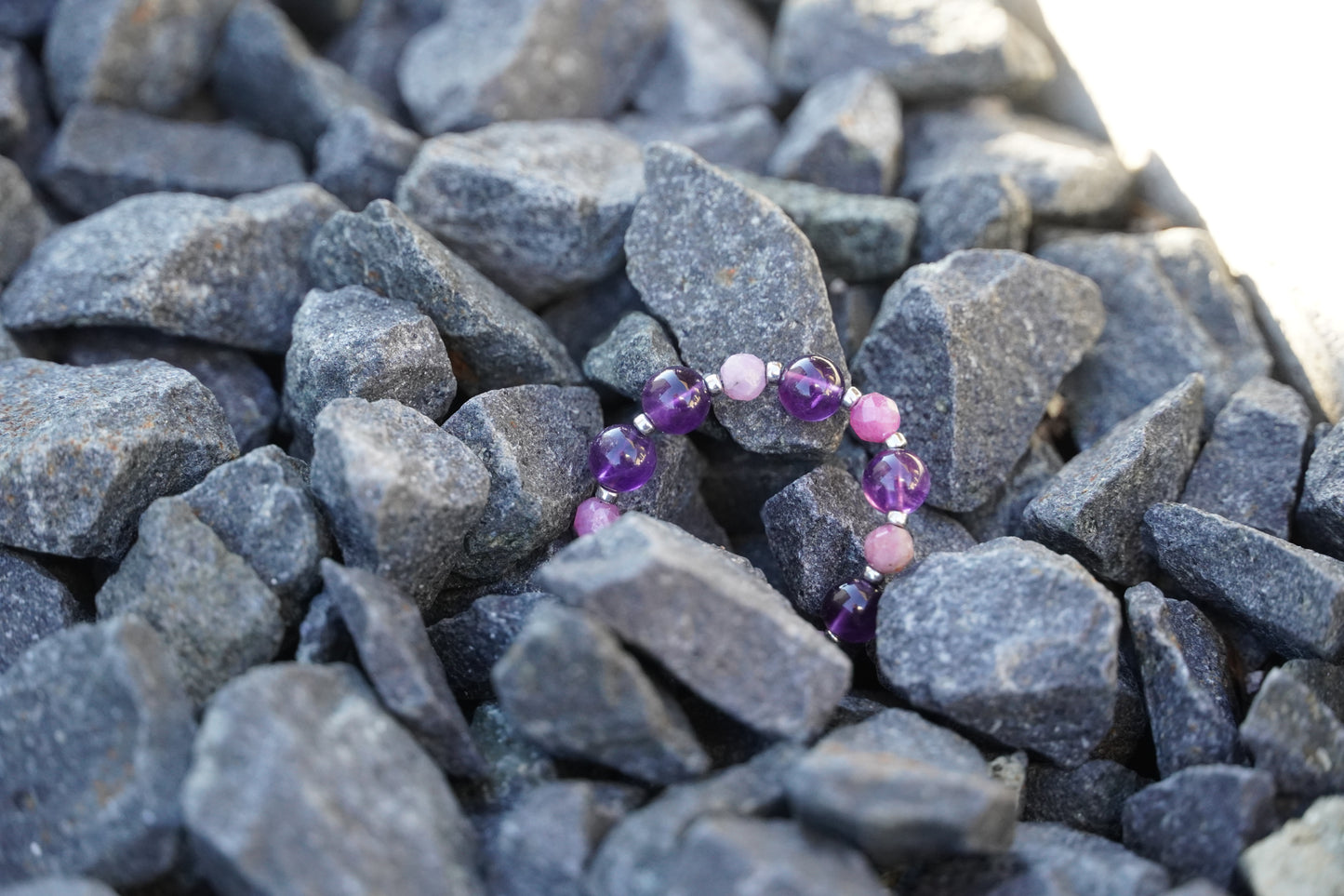 Ring with purple and pink beads on a bed of gray stones