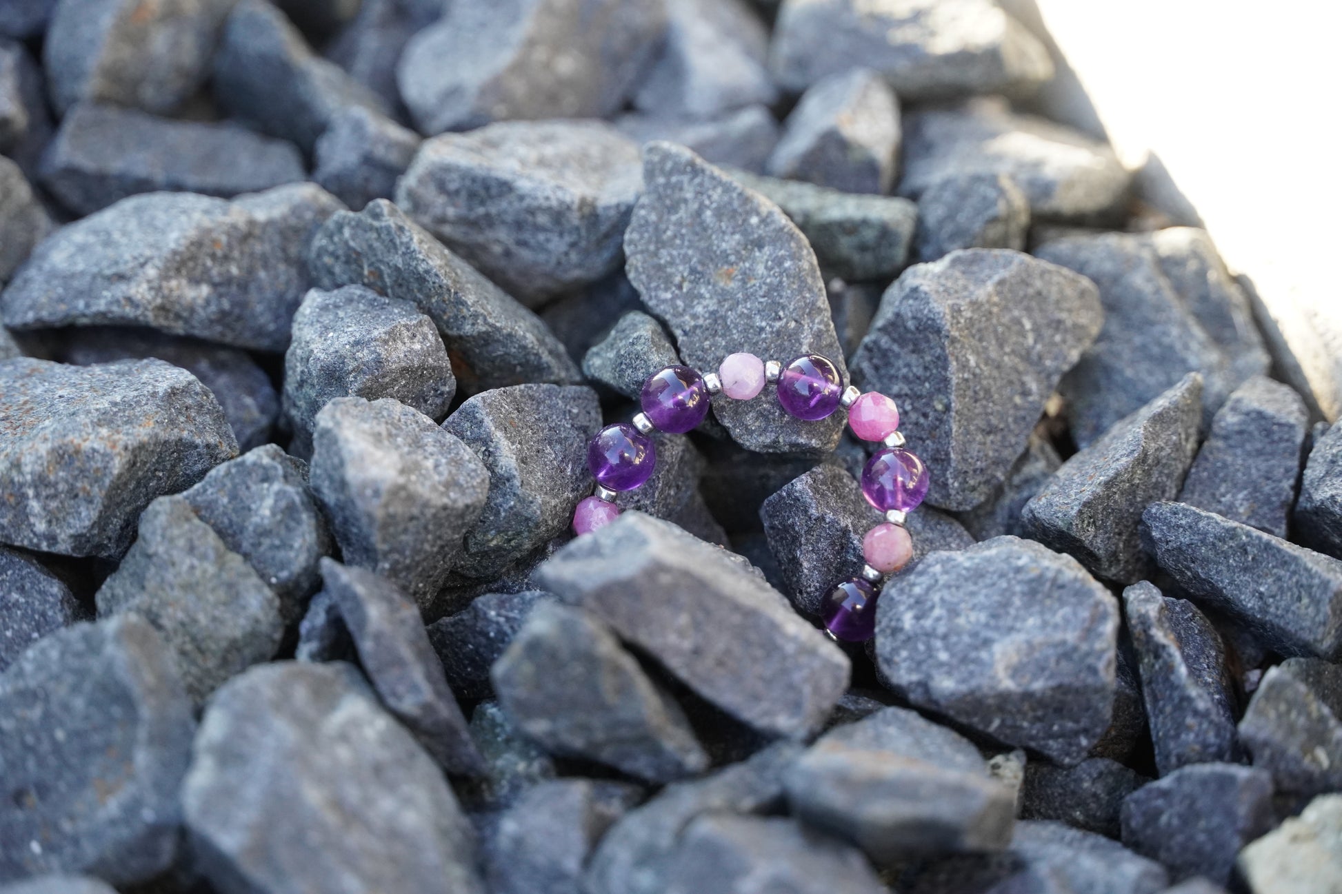 Ring with purple and pink beads on a bed of gray stones