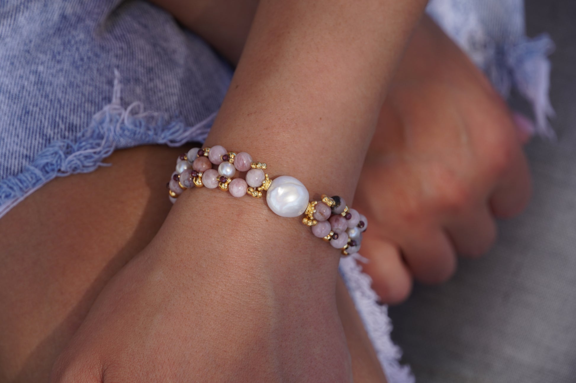 hand wearing a pink bracelet with a baroque pearl