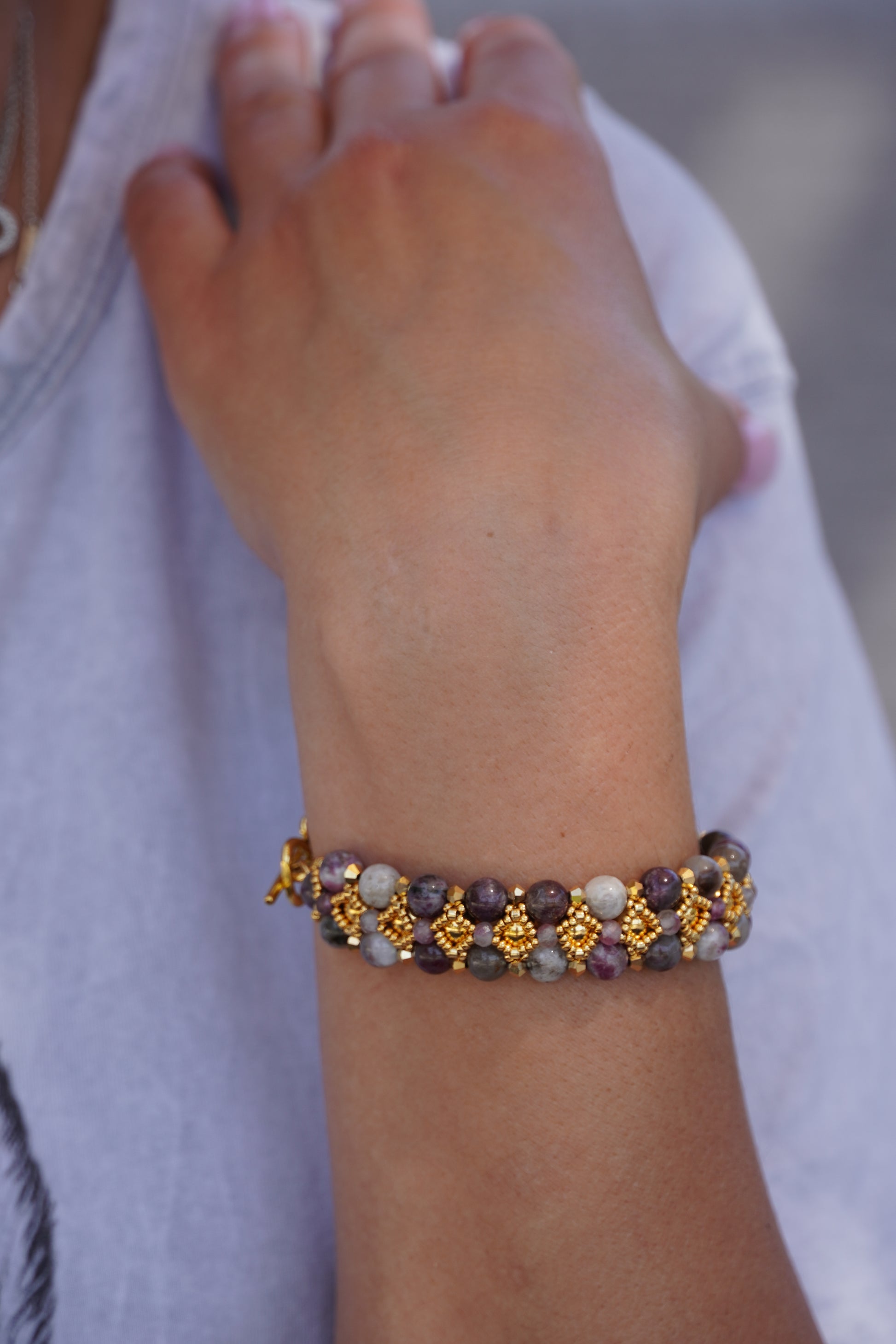 hand wearing a beaded bracelet with tourmaline stones