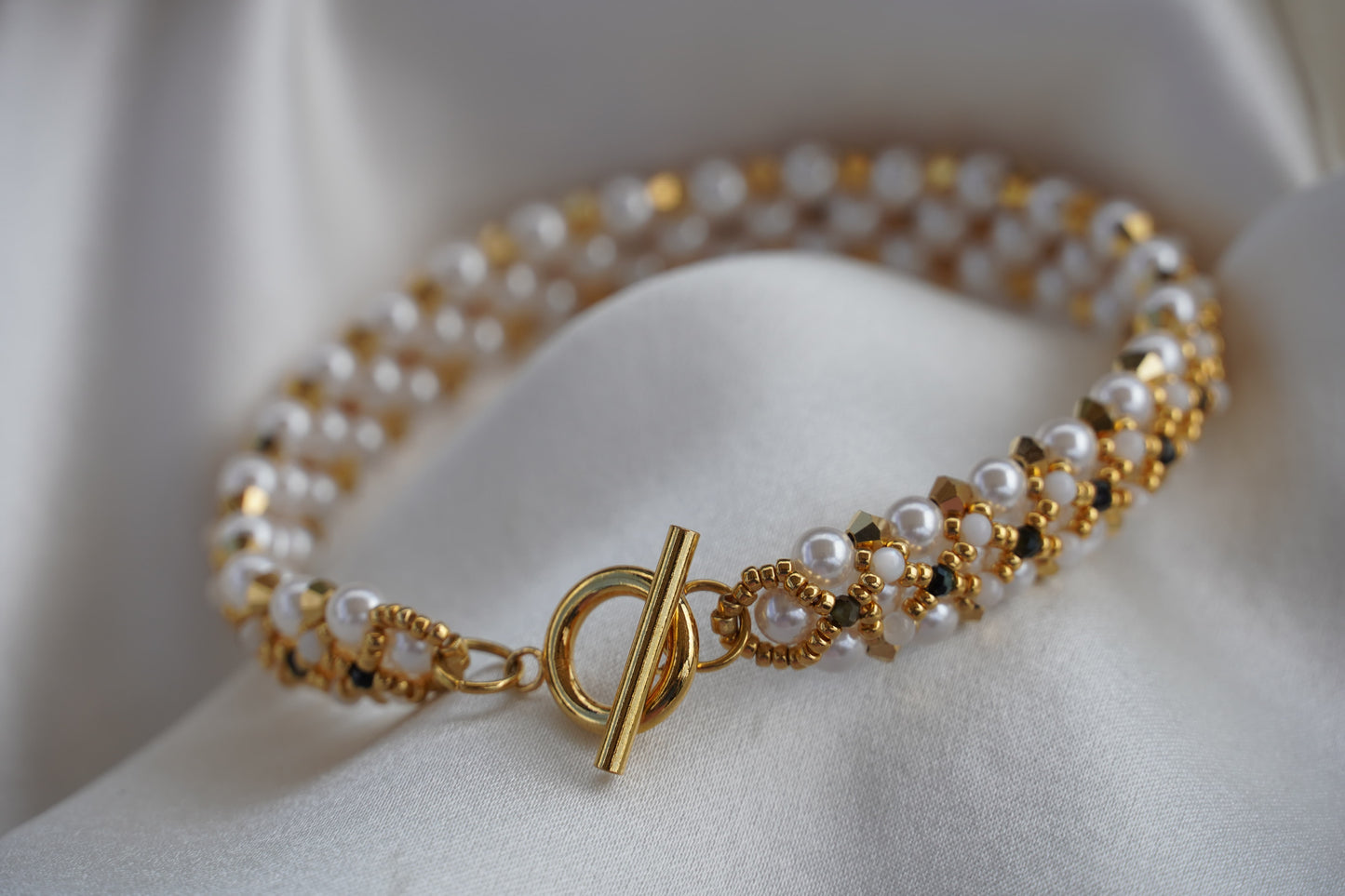 Gold and pearl bracelet on a white surface
