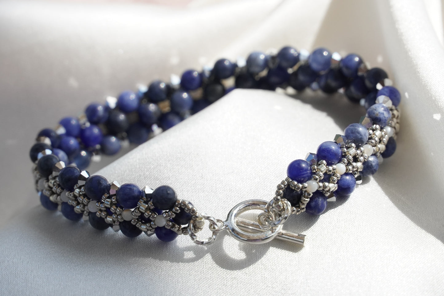 Blue beaded bracelet with silver clasp on a white surface