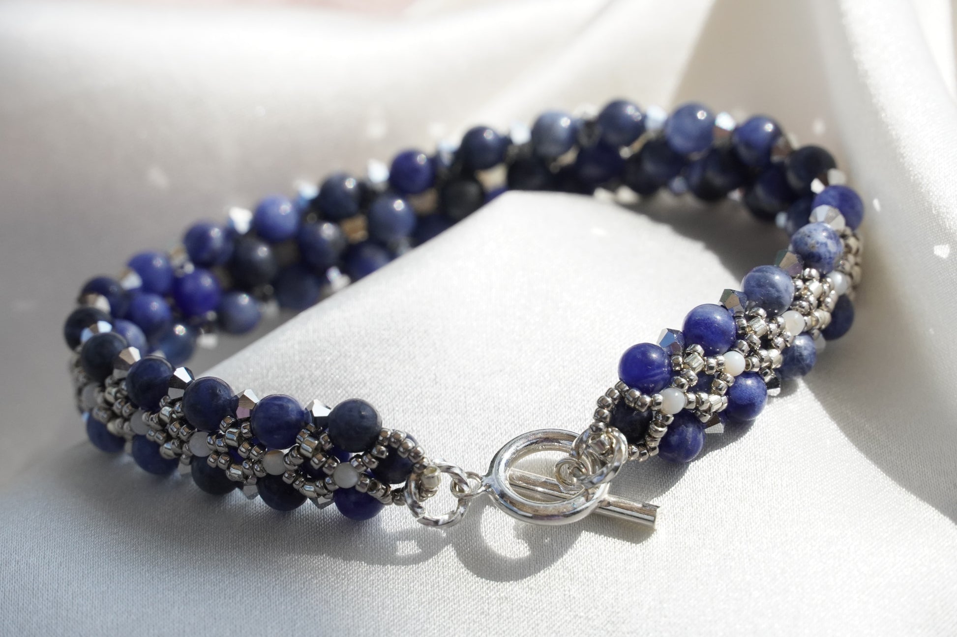 Blue beaded bracelet with silver clasp on a white surface