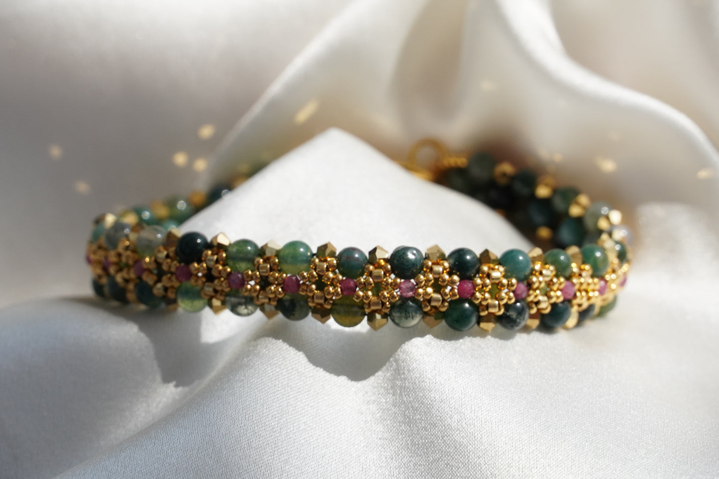 Closeup of a green beaded bracelet with gold accents