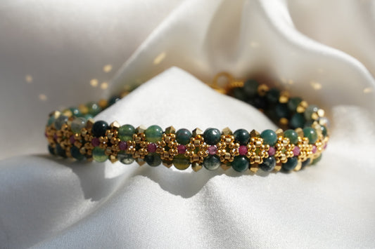 Closeup of a green beaded bracelet with gold accents