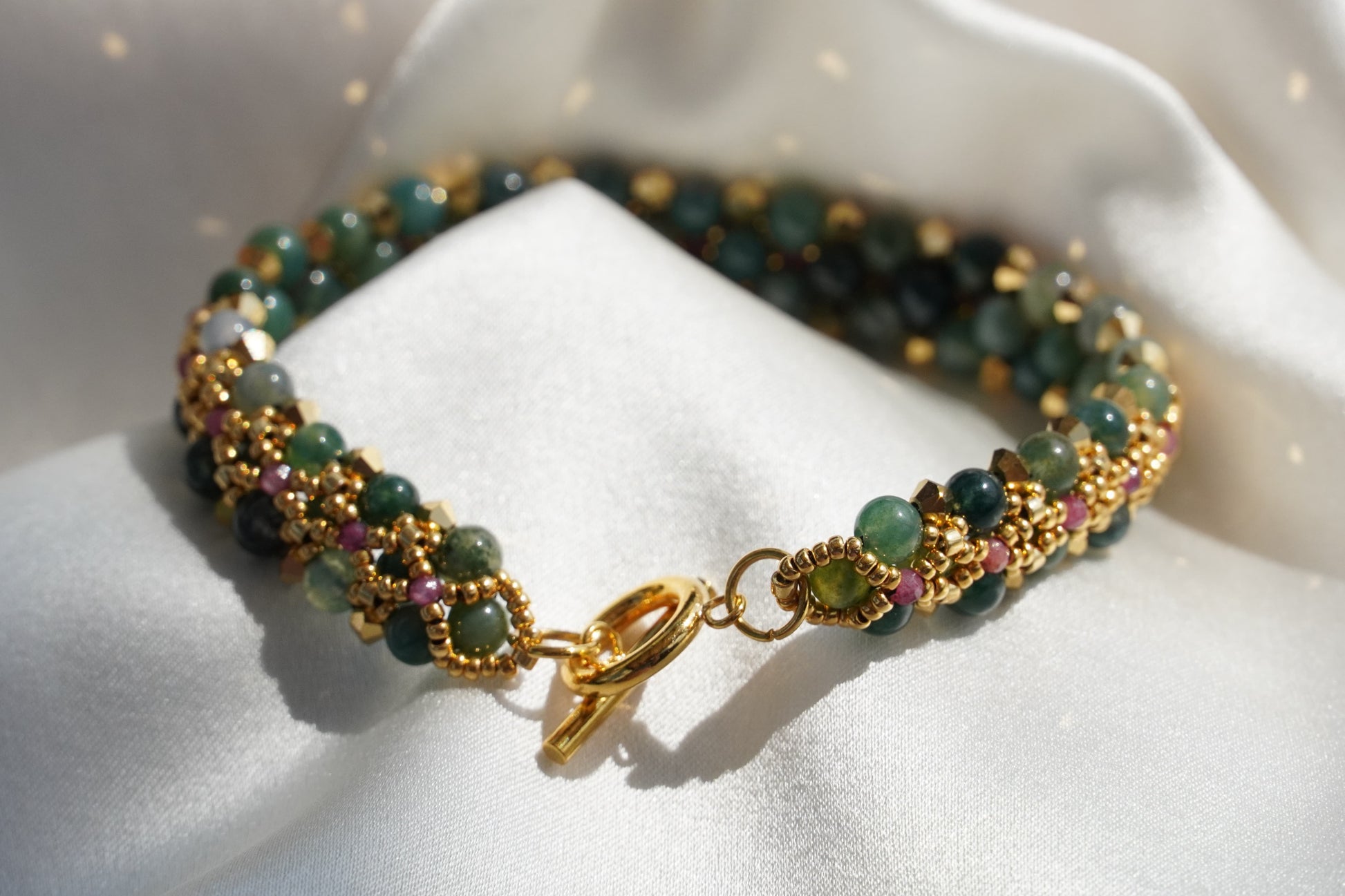 Beaded bracelet with gold clasp on a white fabric background