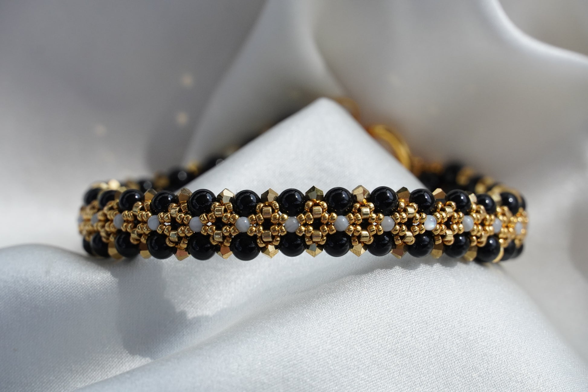 Black and gold beaded bracelet on a white surface