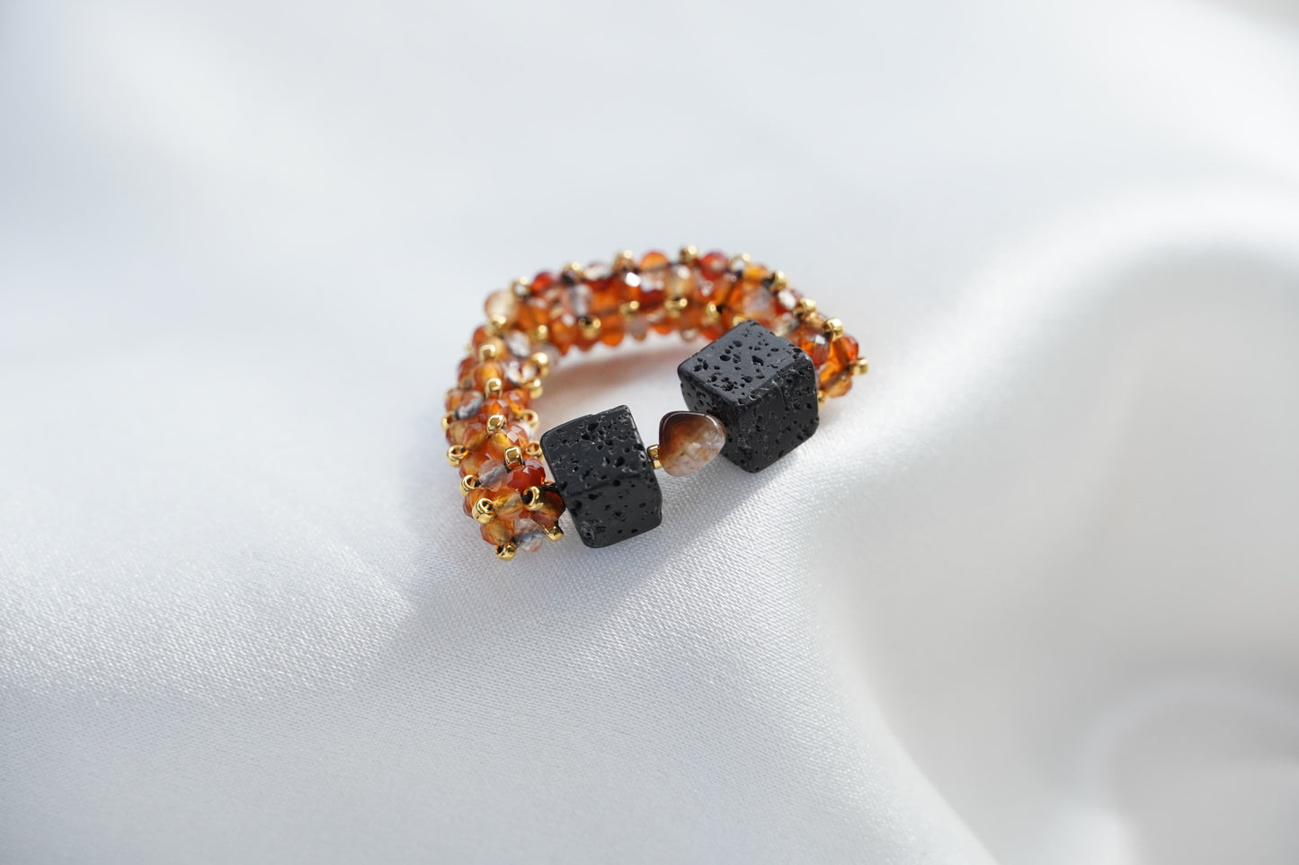 Ring with orange beads and black cube stones on a white background