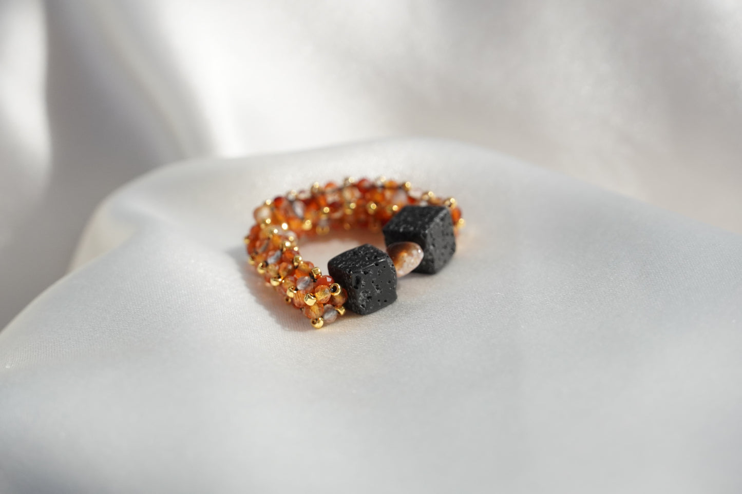 Ring with orange beads and black stones on a white surface