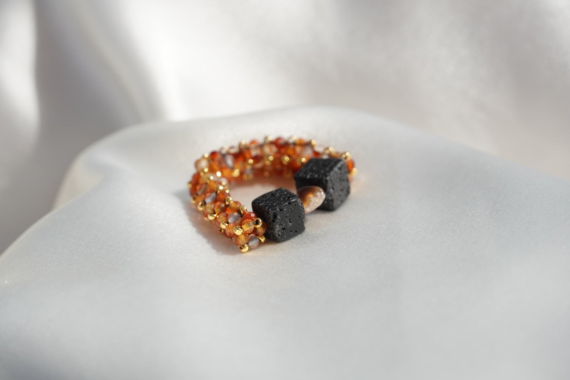 Ring with orange beads and black stones on a white surface
