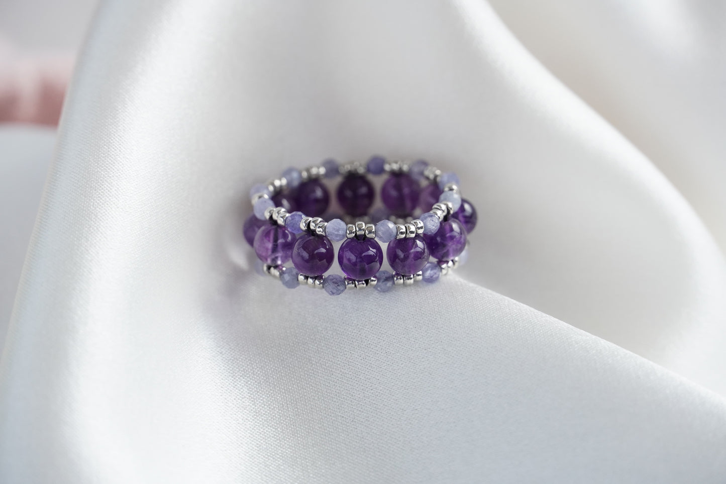 Purple beaded ring on a white fabric background