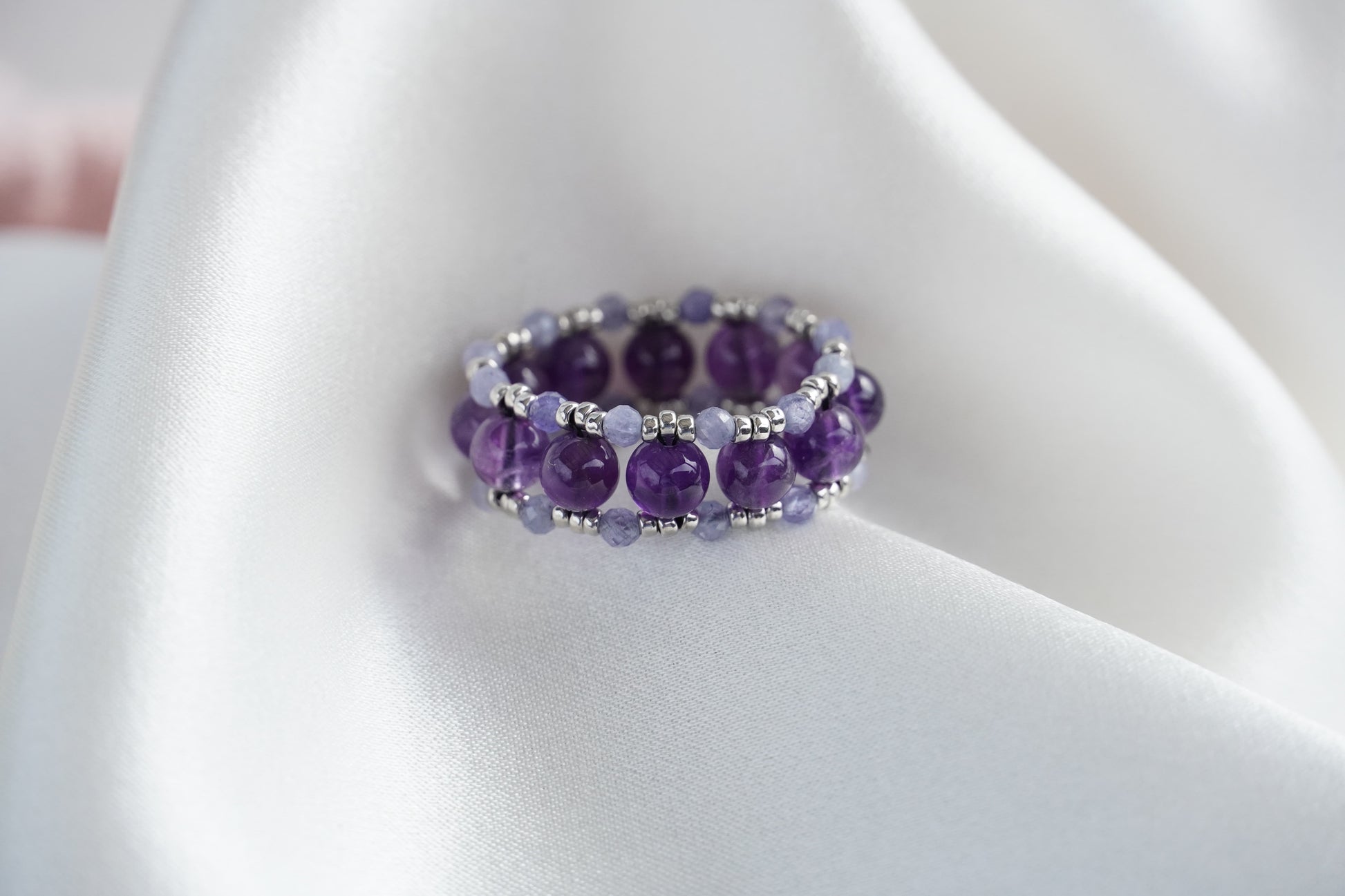 Purple beaded ring on a white fabric background