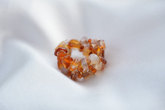 Amber-colored beaded ring on a white fabric background