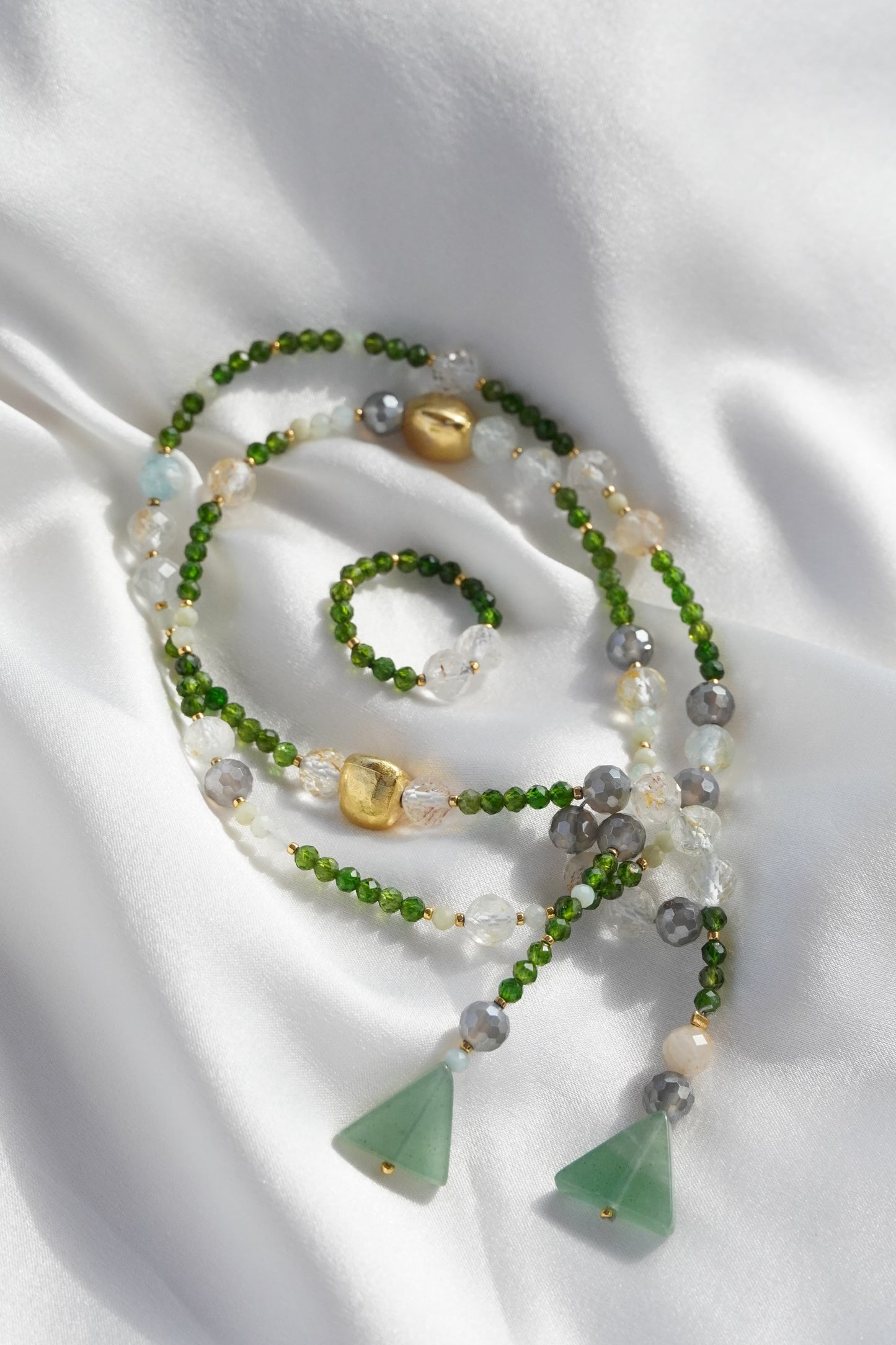 Necklace with green and gold beads on a white fabric background