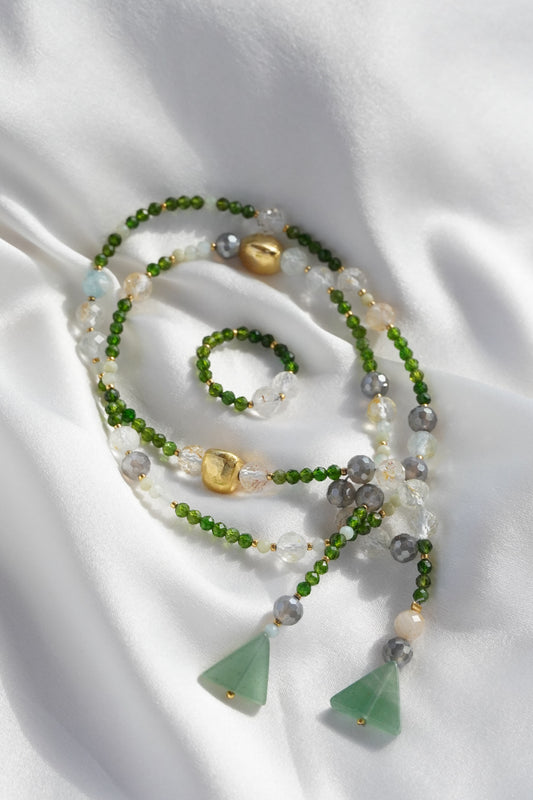 Necklace with green and gold beads on a white fabric background
