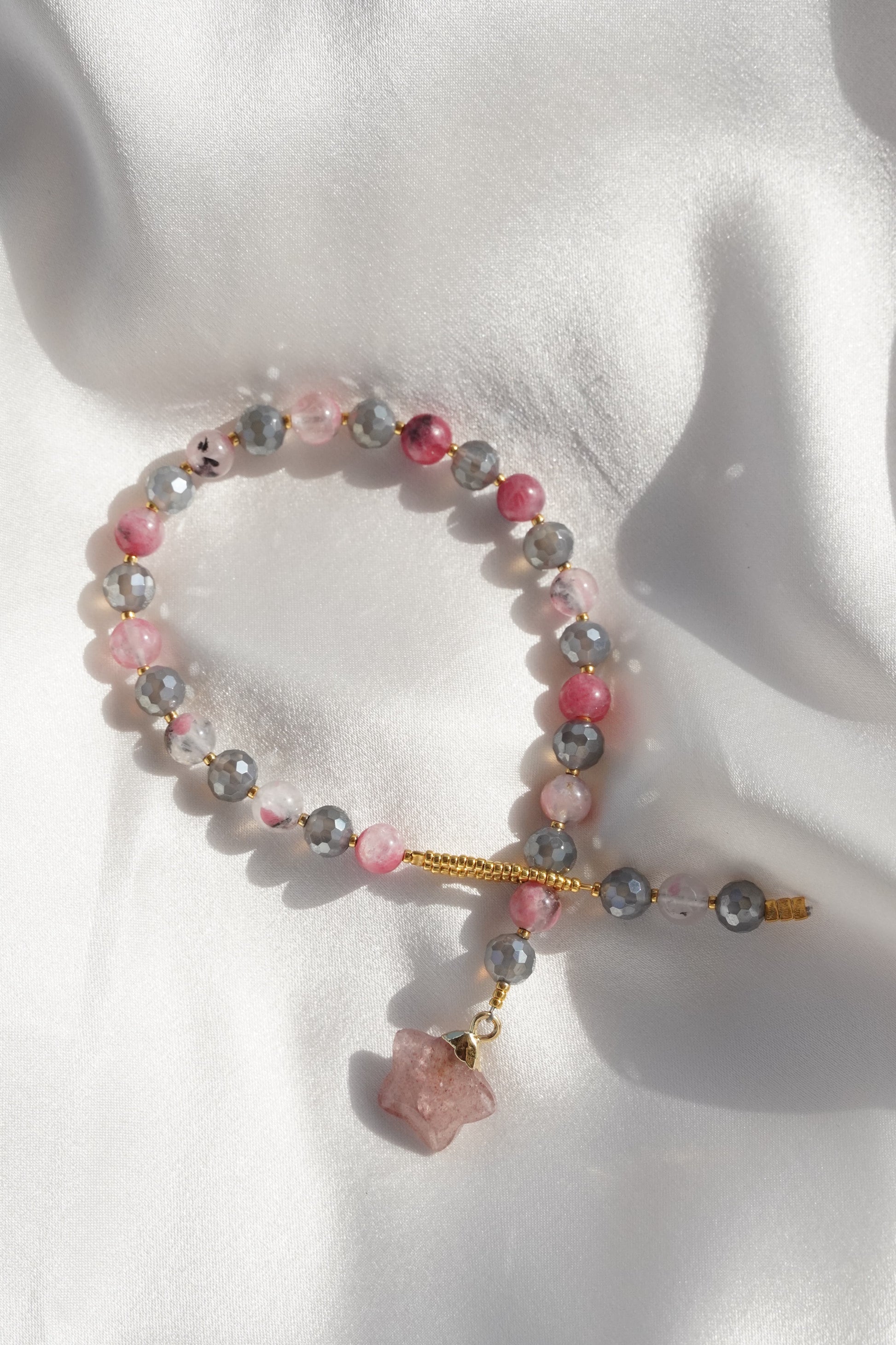 Bracelet with pink and gray beads and a pink star on a white background
